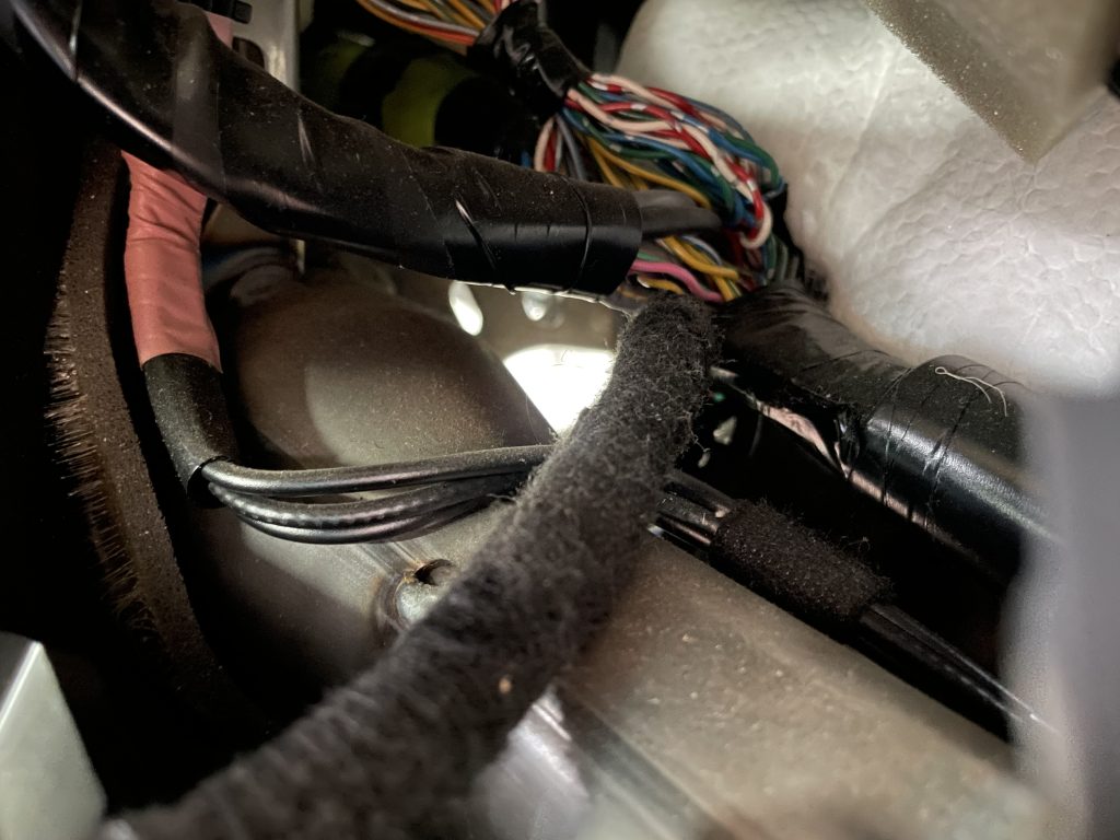 View from passenger seat looking into the space for the radio towards the driver wheel well. Shows a space for where wires can run.